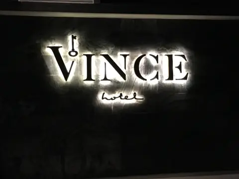 ตัวอักษรไฟ VINCE บนผนังสีดำ