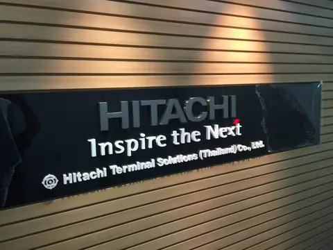ป้าย HITACHI บนผนังไม้ระแนง