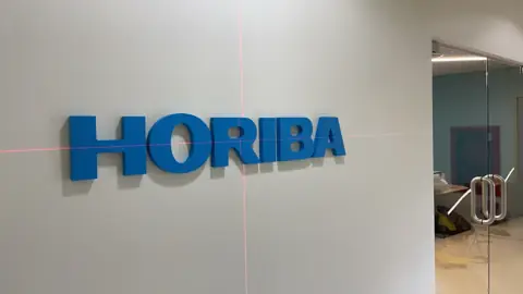 ตัวอักษรสีน้ำเงิน HORIBA บนผนัง
