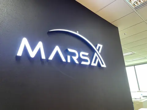 โลโก้ไฟสีขาว MARSA บนผนังสีเข้ม