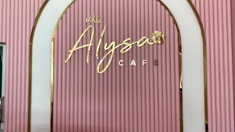 ป้าย Alyssa Cafe สีทองบนผนังชมพู