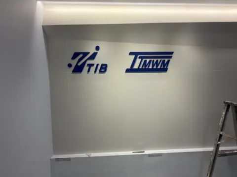 โลโก้บริษัทสองแห่งบนผนังสำนักงาน